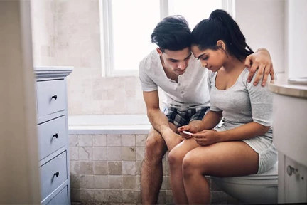 A couple looking at pregnancy test in the bathroom after fertility treatments