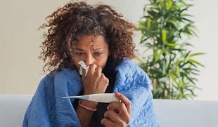 Woman blowing nose and checking body temperature