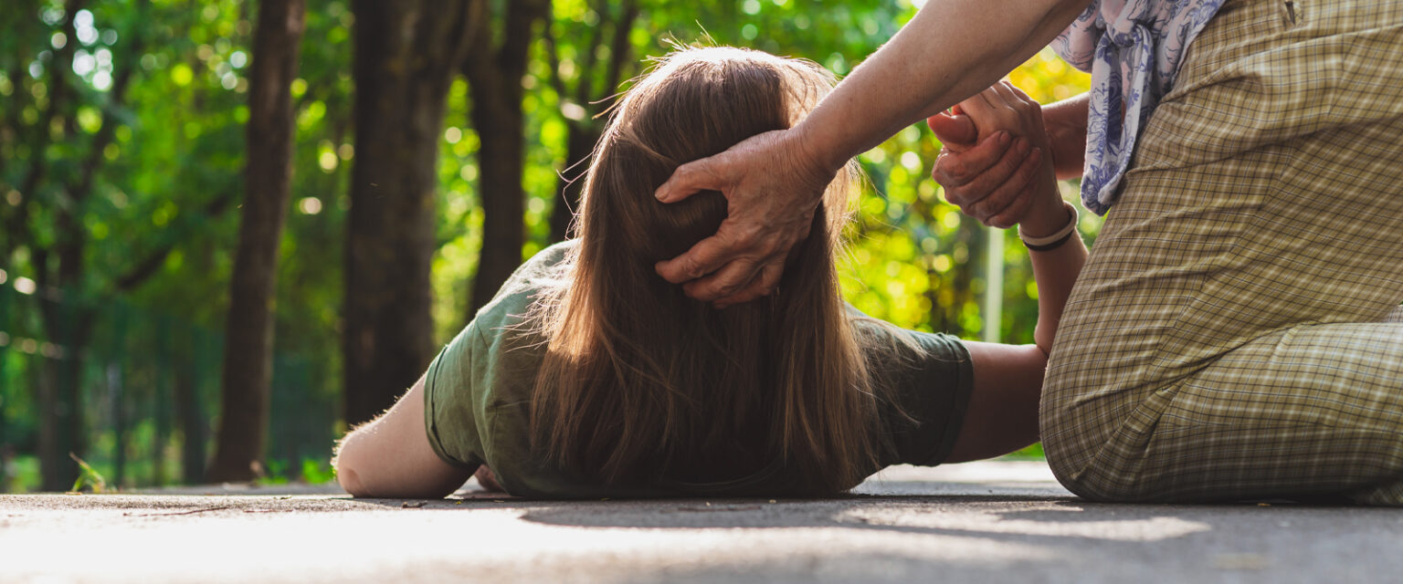 a person support a woman's head, while she lays down