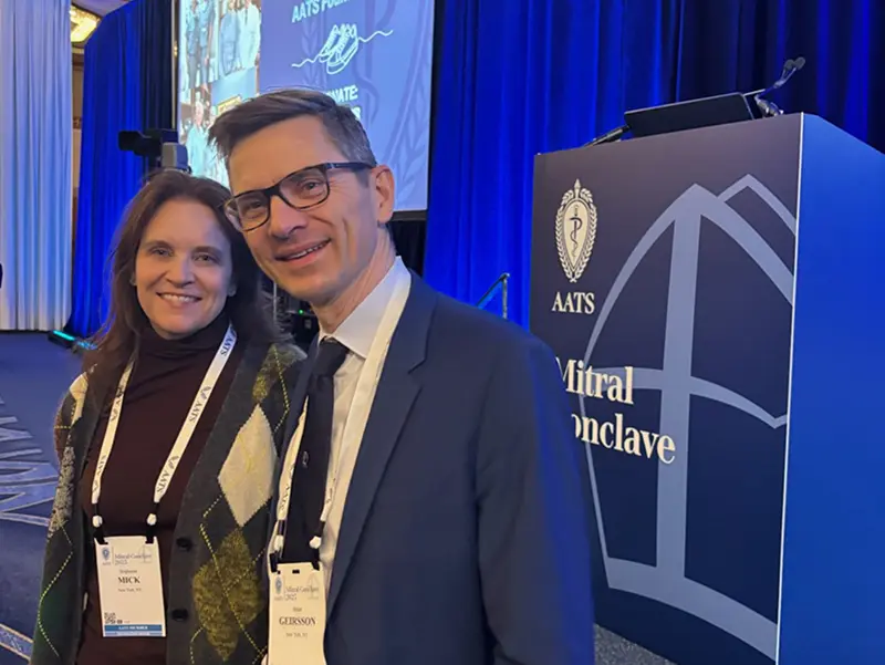 Dr. Stephanie Mick and Dr. Arnar Geirsson standing next to each other in front of a podium at the AATS Mitral Conclave.