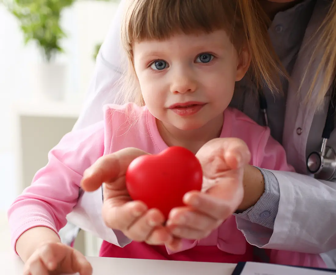 little girl looking at the camera with a heart toy in hands